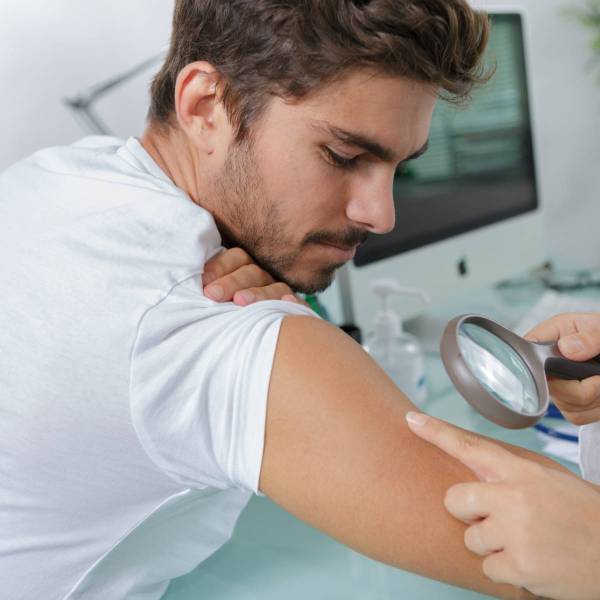 Close-up of doctors hands checking mans mole